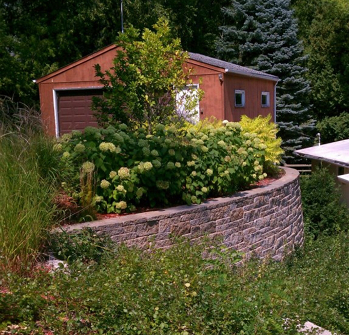 A flower garden is made with a retaining wall